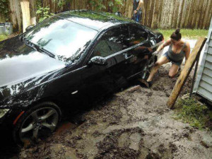 Elizabeth Lyons works at getting the car off the piece of metal that was hidden in a pothole in her downtown Oldsmar yard. (Credit: Elizabeth Lyons)